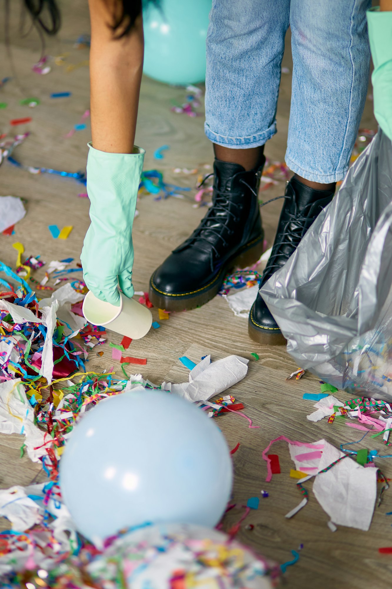 Woman cleaning mess of floor in room after party, removes garbage from the floor